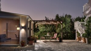 A reception area with a checkered pergola, stone flooring, and potted plants. - Katerina Studios (Planos)