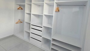 Et hvidt walk-in closet med mange hylder og opbevaringsplads til tøj.