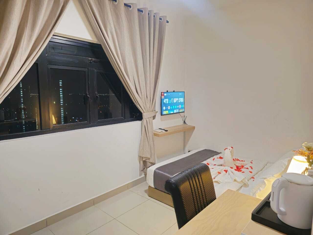 Una habitación pequeña con una cama, un escritorio, una silla, un televisor y una ventana con cortinas.