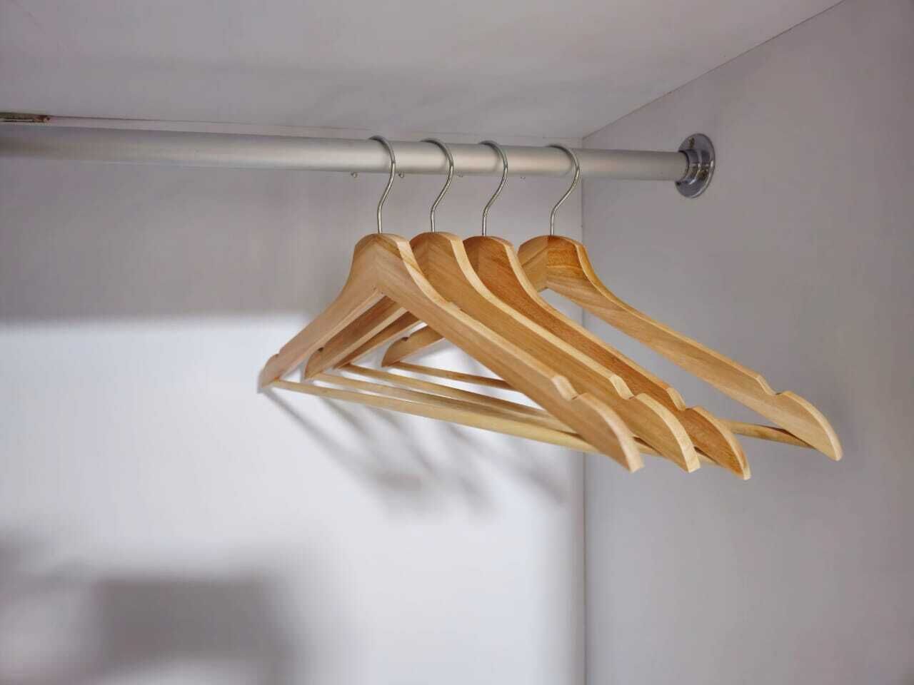Eine Metallstange mit daran hängenden Holz-Kleiderbügeln.