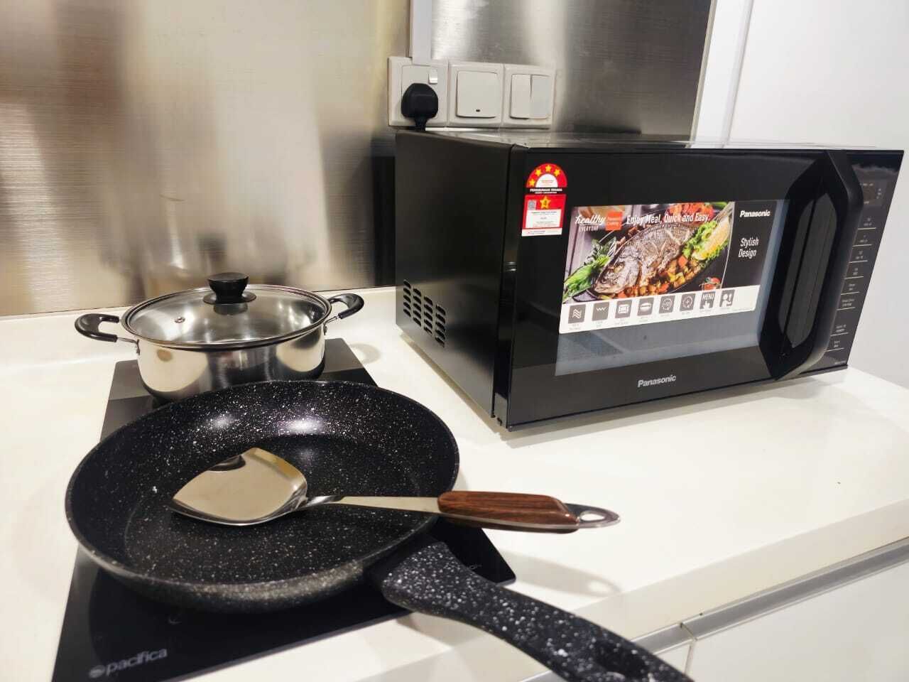 Una cocina con microondas, sartén y olla sobre la estufa.