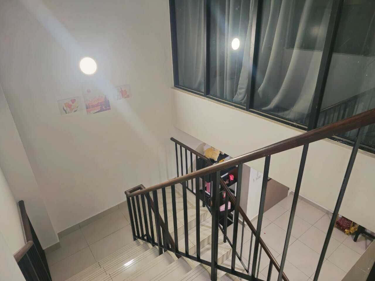 A staircase with a metal railing leading to a room with a window, a radiator, and a small table with items on it.