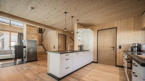 Une cuisine moderne avec des murs en bois et un îlot central, un four encastré et un réfrigérateur en acier inoxydable.