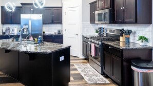 Una cocina moderna con armarios oscuros, electrodomésticos de acero inoxidable y una encimera de granito.