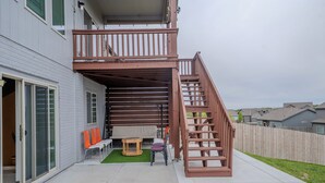 Un edificio residencial con balcón, escaleras y un pequeño patio amoblado.