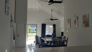 Ein stilvoller Essbereich mit Tisch und Stühlen, einem Deckenventilator und Kunstwerken an den Wänden.