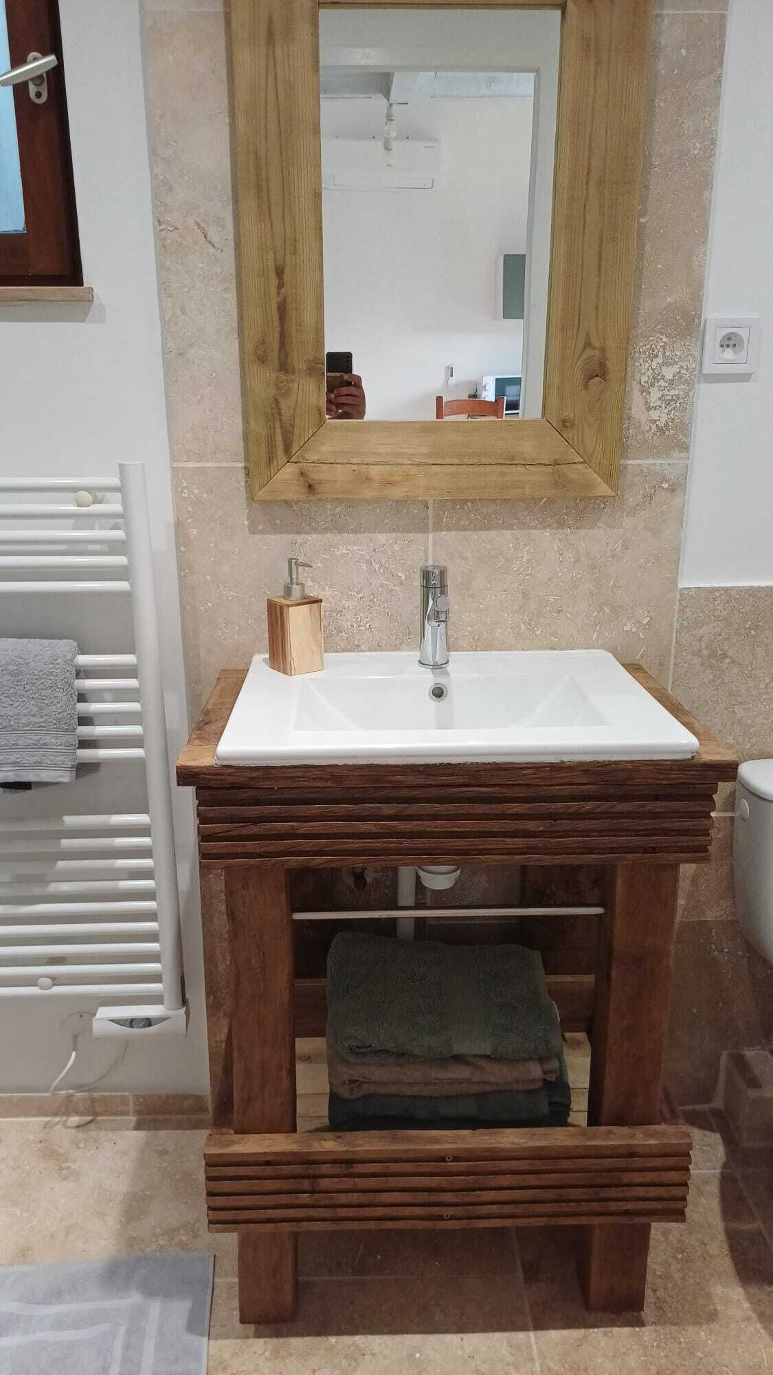 Une salle de bain avec un meuble-lavabo en bois, un lavabo blanc, un miroir et un porte-serviettes.