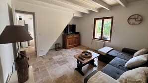 A living room with a sofa, a coffee table, a lamp, a TV, and a window.