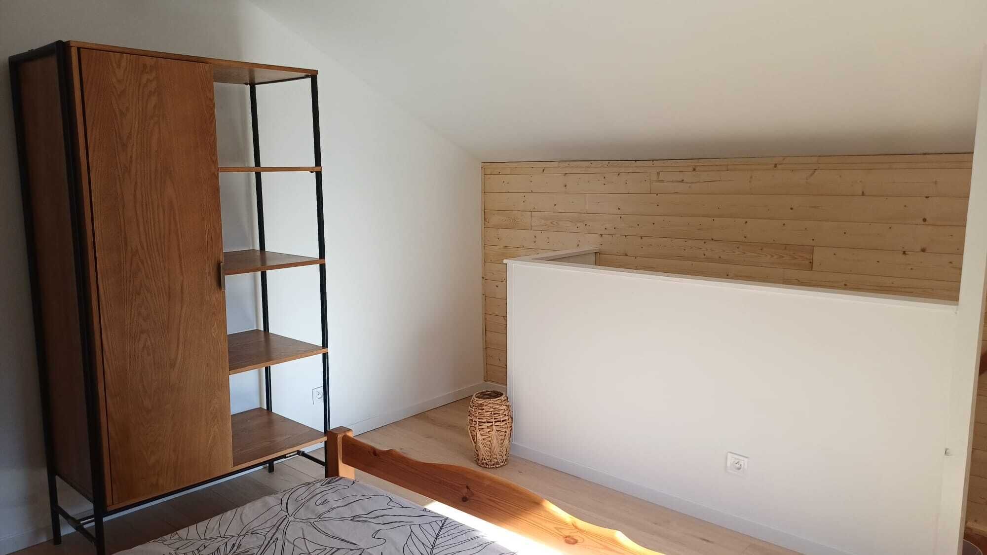 Quarto com guarda-roupa de madeira, parede branca e teto de ripas de madeira.