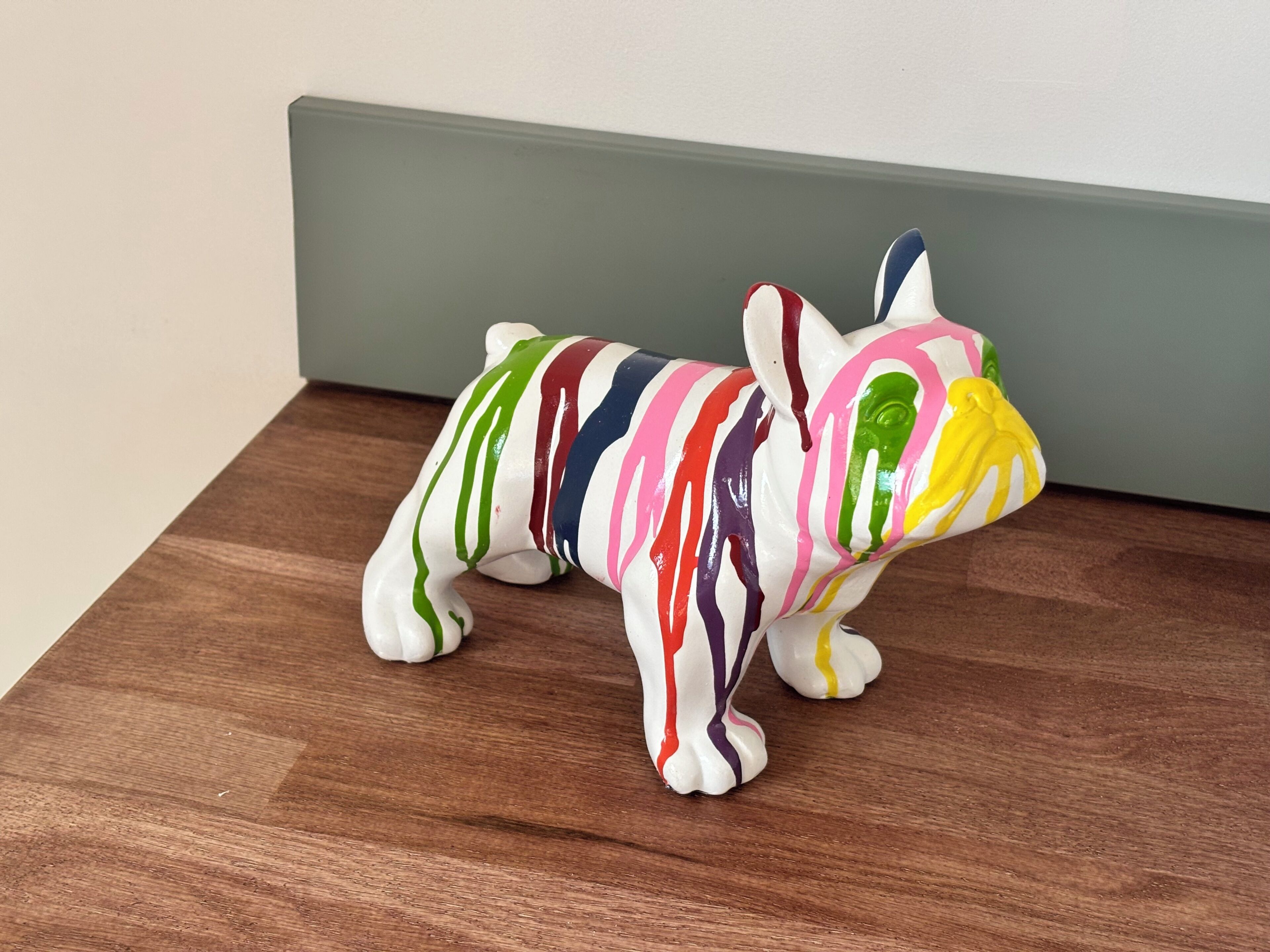Eine bunte Hundfigur auf einer Holztischplatte.