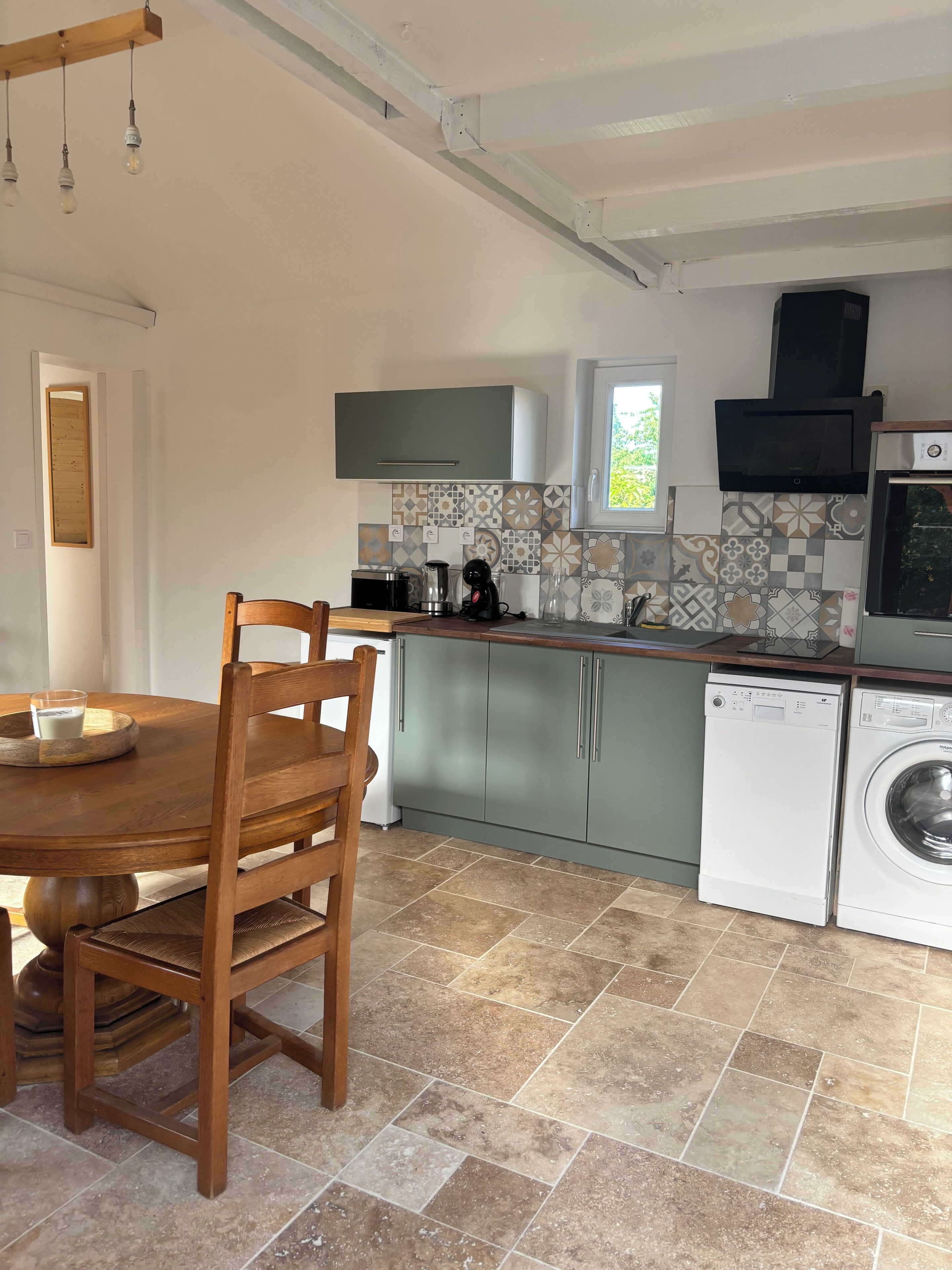 Een keuken met een eettafel, stoelen, een wasmachine en een magnetron.