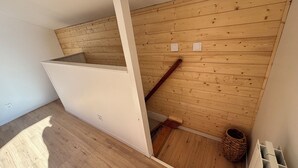 A staircase with wooden walls, a white wall, and a wooden floor.