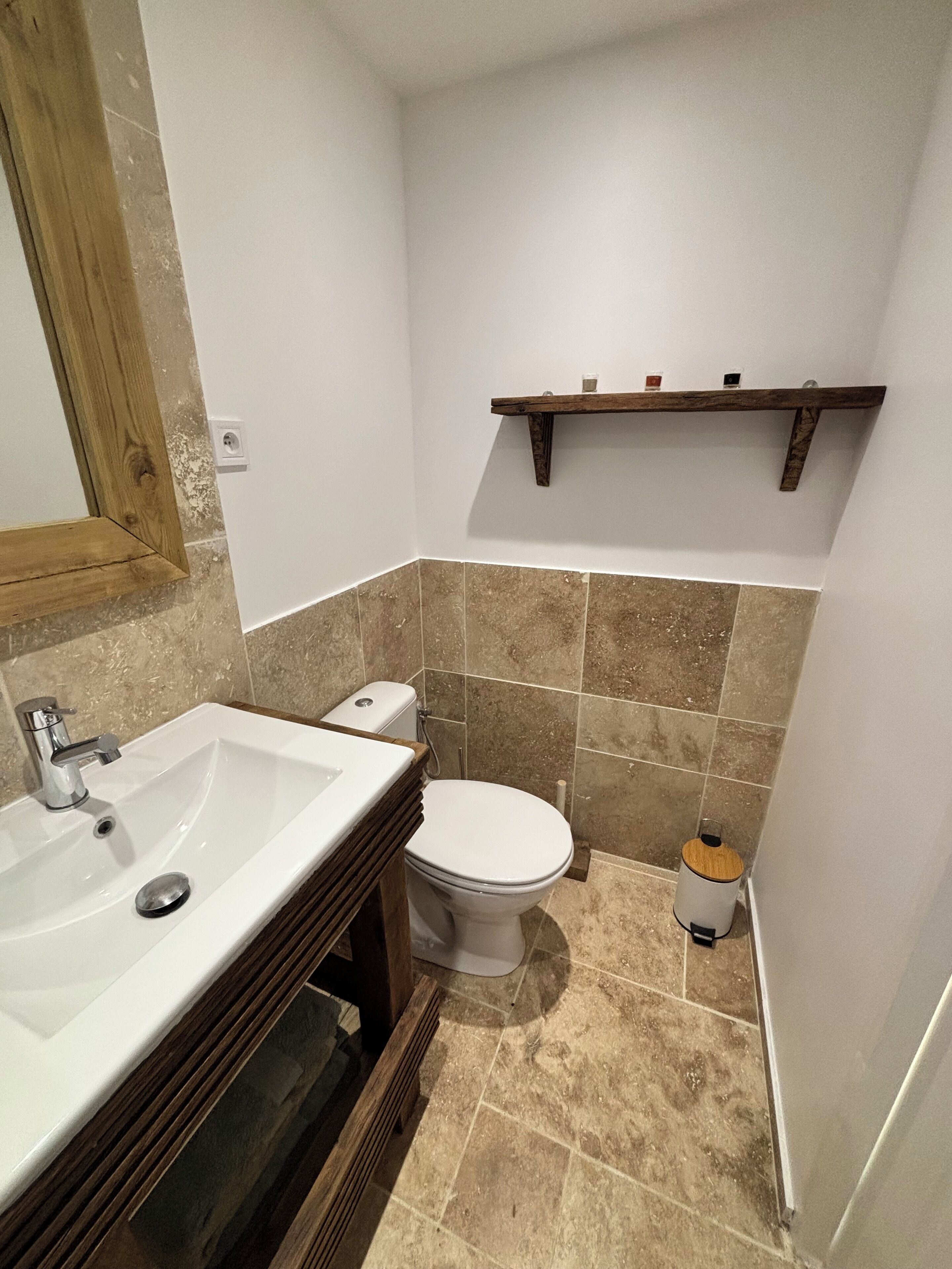A bathroom with a sink, toilet, and a shelf above the toilet.
