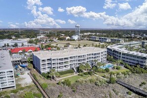 Un hotel de varios pisos con un patio central, una torre de agua y un puente al fondo.