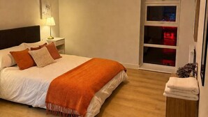 A bedroom with a bed, bedside lamp, and a wooden nightstand. - Spacious 2 Bed apartment Rainham LDN Gated Parking (Greater London)