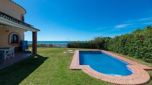 A swimming pool with a brick border, a patio with a table and chairs, and a view of the sea. - LXR Villa Sirena Oceanfront 3-Bedroom (El Faro)