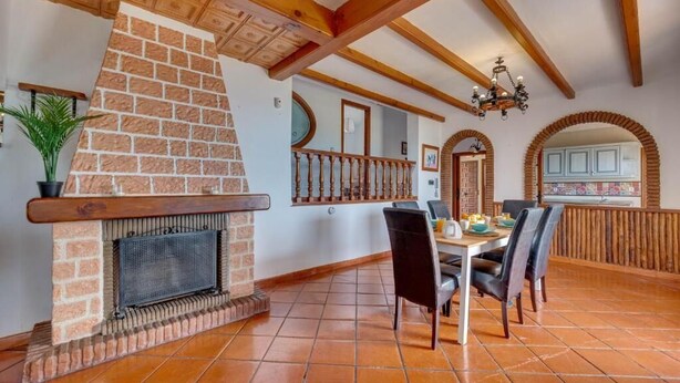 A dining area with a brick fireplace, wooden beams, and a tiled floor. - LXR Villa Sirena Oceanfront 3-Bedroom (El Faro)