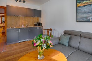 A modern kitchen with grey cabinets, a wooden countertop, and a dining area with a table and chairs. - Bungalow im Ferienresort Damerow auf Usedom (Koserow)