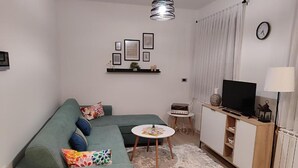 Una sala de estar moderna con un sofá verde, una mesita redonda, un televisor y un radiador.