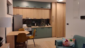 Cocina compacta con armarios de madera, una mesa de comedor con sillas y un sofá con un cojín colorido.