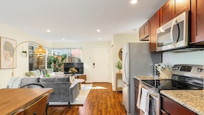 A modern kitchen with wooden cabinets, stainless steel appliances, and a dining area with a wooden table and chairs. - Designated Parking · AC · Walks to Space Needle/DT (Seattle)