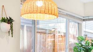 A room with two green upholstered chairs, a wicker pendant light, and a view through a large window. - Designated Parking · AC · Walks to Space Needle/DT (Seattle)
