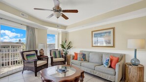 A living room with a ceiling fan, a sofa, a coffee table, and a view of the outside. - Ocean‑View Condo in Beachside Colony • Pools • Steps to the Sand • Restaurant (Tybee Island)