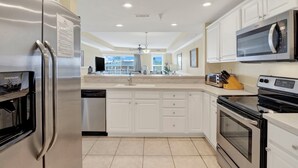 A modern kitchen with white cabinetry, stainless steel appliances, and a built-in oven. - Ocean‑View Condo in Beachside Colony • Pools • Steps to the Sand • Restaurant (Tybee Island)
