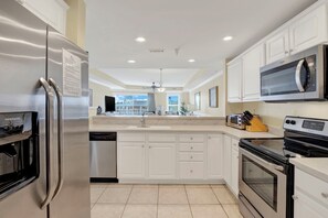 A modern kitchen with white cabinetry, stainless steel appliances, and a built-in oven. - Ocean‑View Condo in Beachside Colony • Pools • Steps to the Sand • Restaurant (Tybee Island)