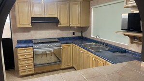 A kitchen with wooden cabinets, a stove, a sink, and a ceiling fan. - LOFT SN1 FOR 2 PEOPLE WITH PARKING AND AMENITIES (San Nicolás de los Garza)