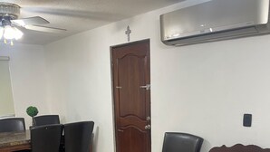 A room with a dining table, chairs, a brown sofa, a ceiling fan, and an air conditioning unit. - LOFT SN1 FOR 2 PEOPLE WITH PARKING AND AMENITIES (San Nicolás de los Garza)