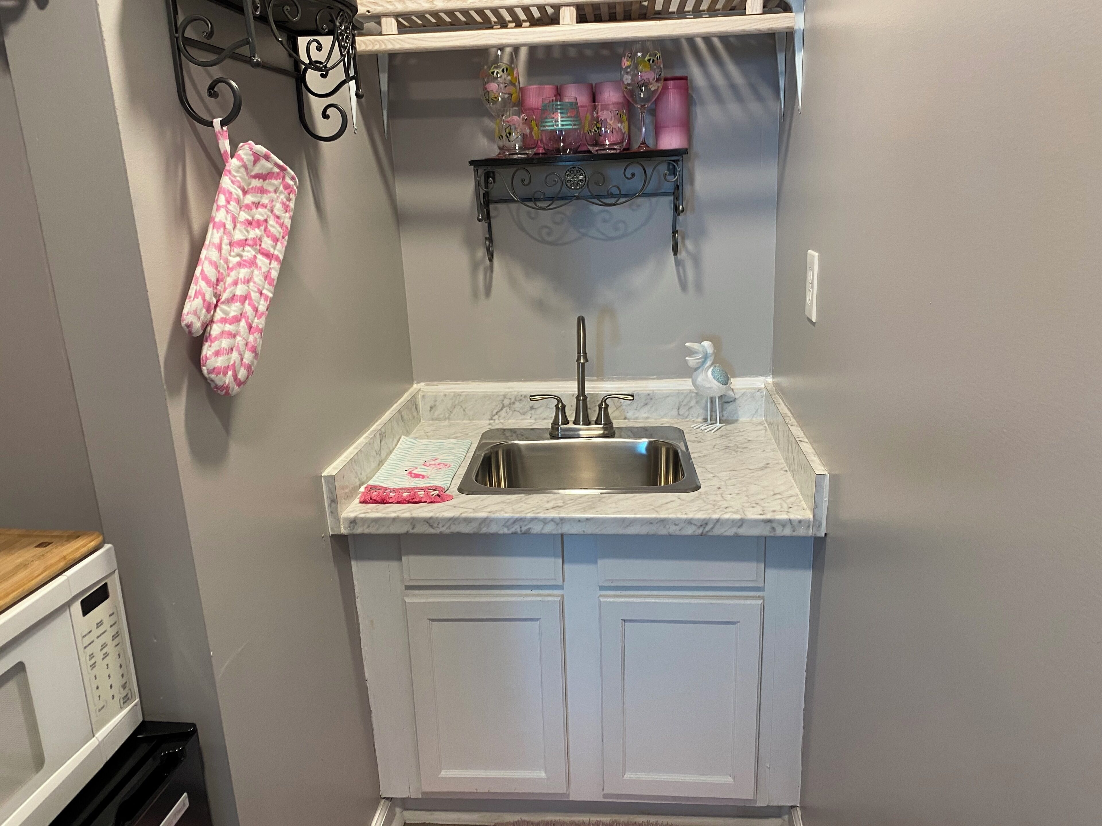 A compact kitchen with a sink, a microwave, and a white cabinet.