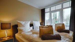 Ein Hotelzimmer mit Bett, Kissen, einem Nachttisch mit Lampe und einem Fenster mit Vorhängen.