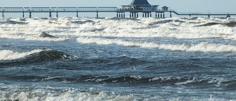 A pier extending into the sea with a building at the end.