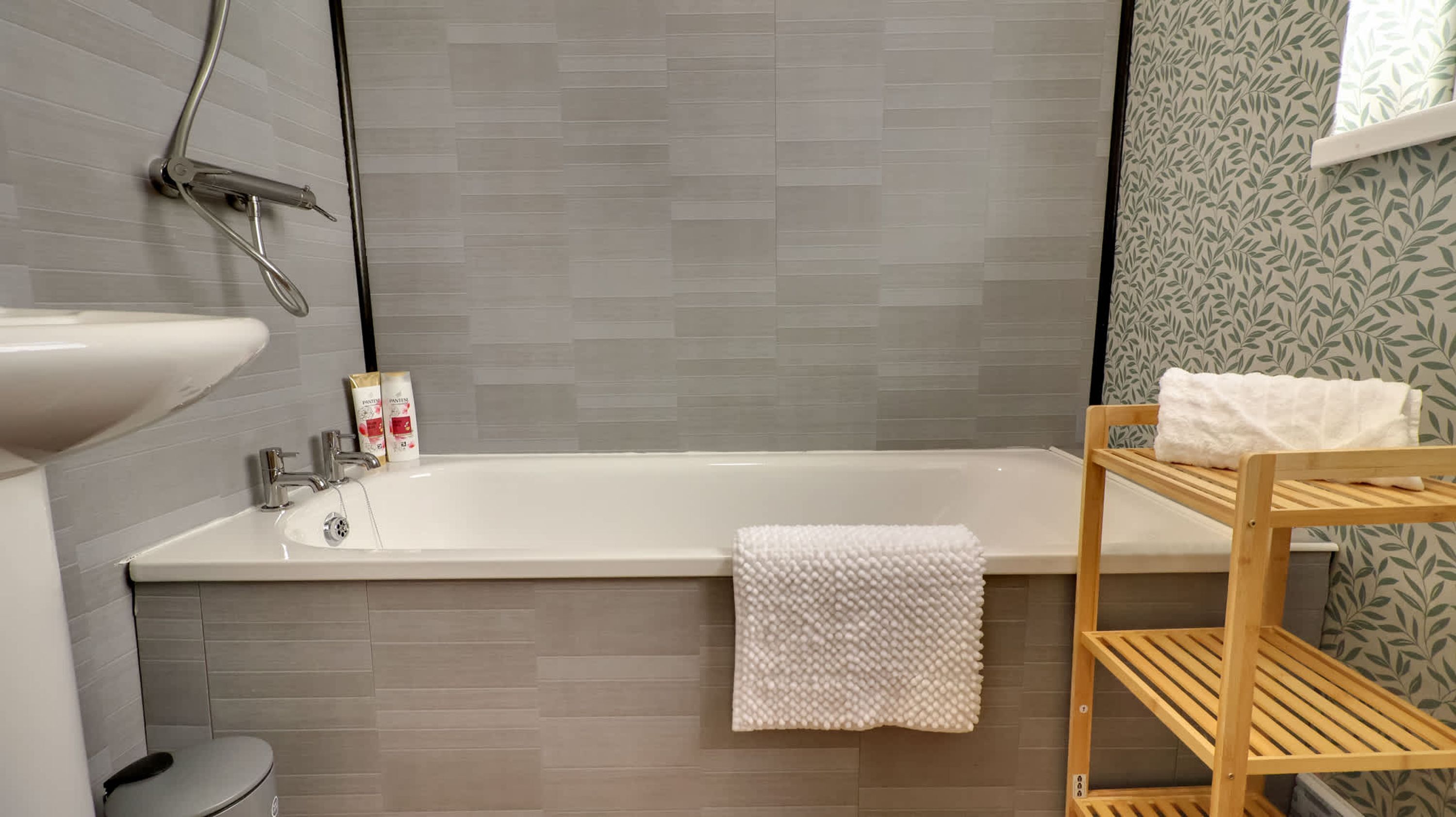 Un bagno con una vasca, un lavandino, un water e uno scaffale con un asciugamano.