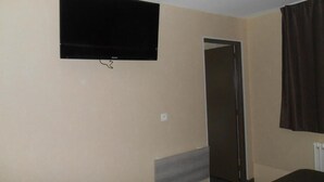 Una habitación con un televisor de pantalla plana montado en la pared, una puerta y una ventana con cortinas.