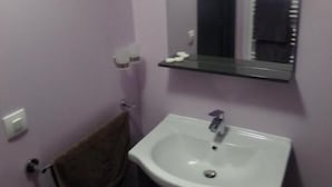 Un baño con un lavamanos blanco, un espejo y una toalla colgada en un perchero.