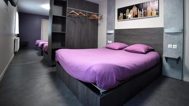 Un dormitorio moderno con una cama grande, estanterías empotradas y un televisor montado en la pared.