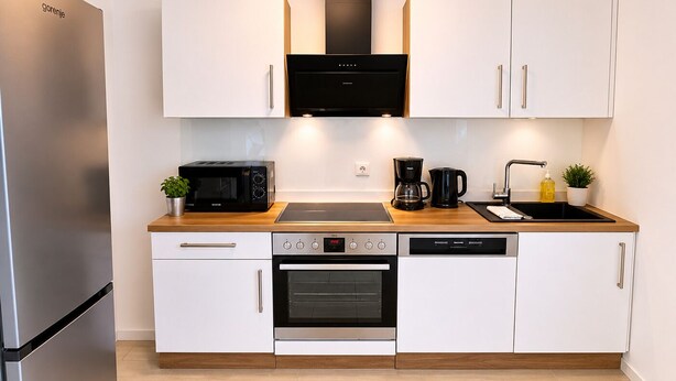 Una cocina moderna con microondas integrado, cafetera, horno y lavavajillas.