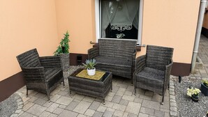Un patio con muebles de mimbre, una mesita y plantas en macetas.