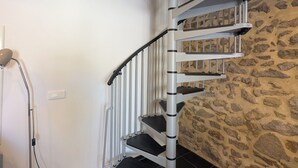 Uma escada em espiral com uma parede de pedra de um lado e uma parede branca do outro.