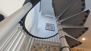 Um quarto moderno em estilo industrial, com escada de metal, parede de pedra e unidade de ar condicionado montada.