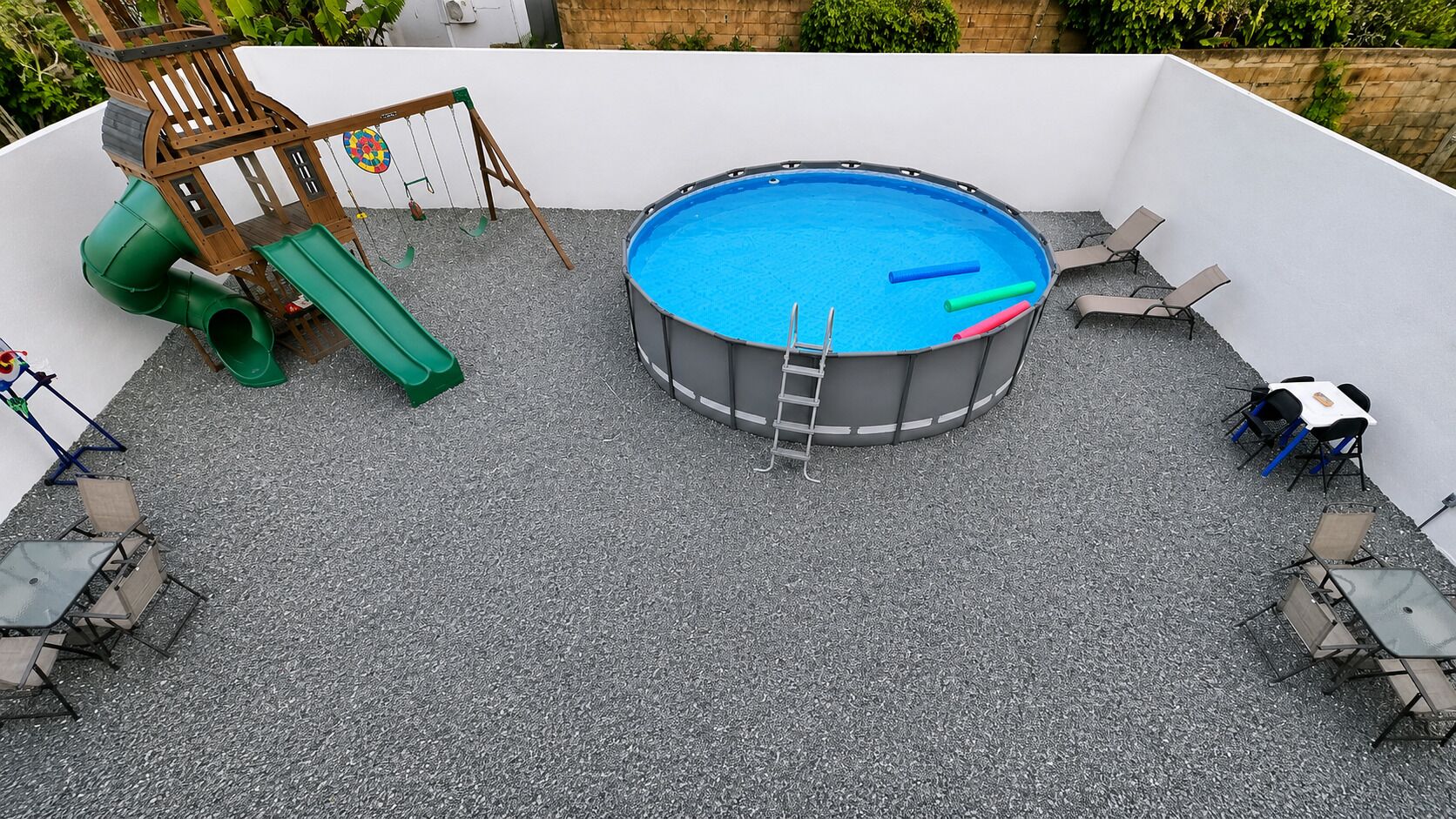 A rooftop pool with a slide, a ladder, and lounge chairs.