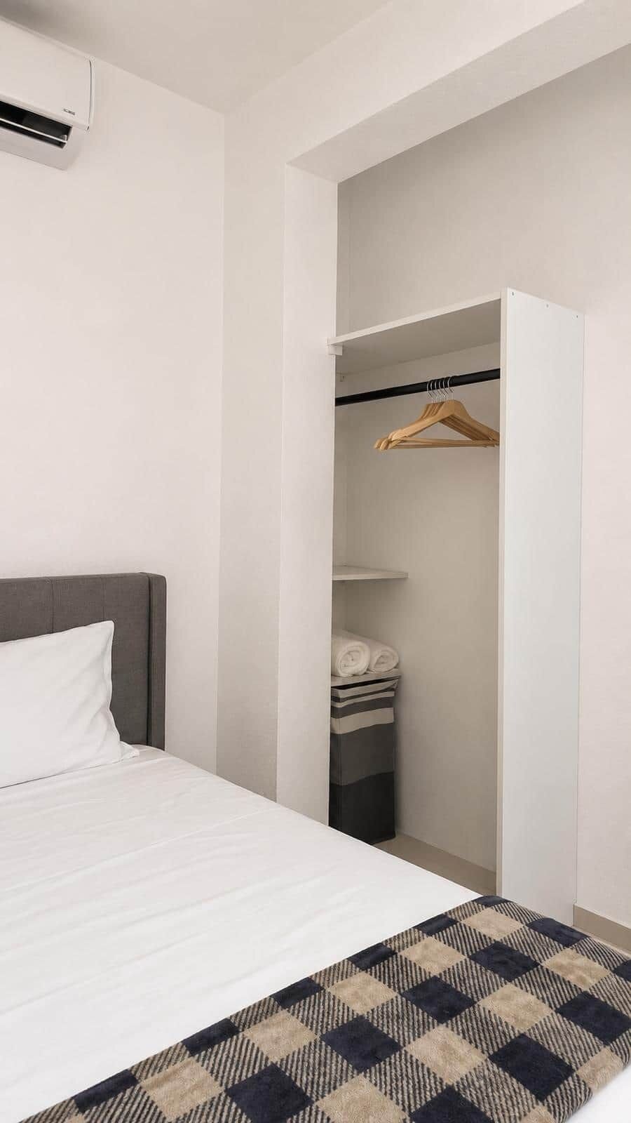 Ein Hotelzimmer mit Bett, Kleiderschrank und Kleiderstange.