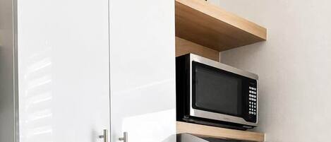 A modern kitchen with stainless steel appliances, a sink, and a wooden shelf with a plant.