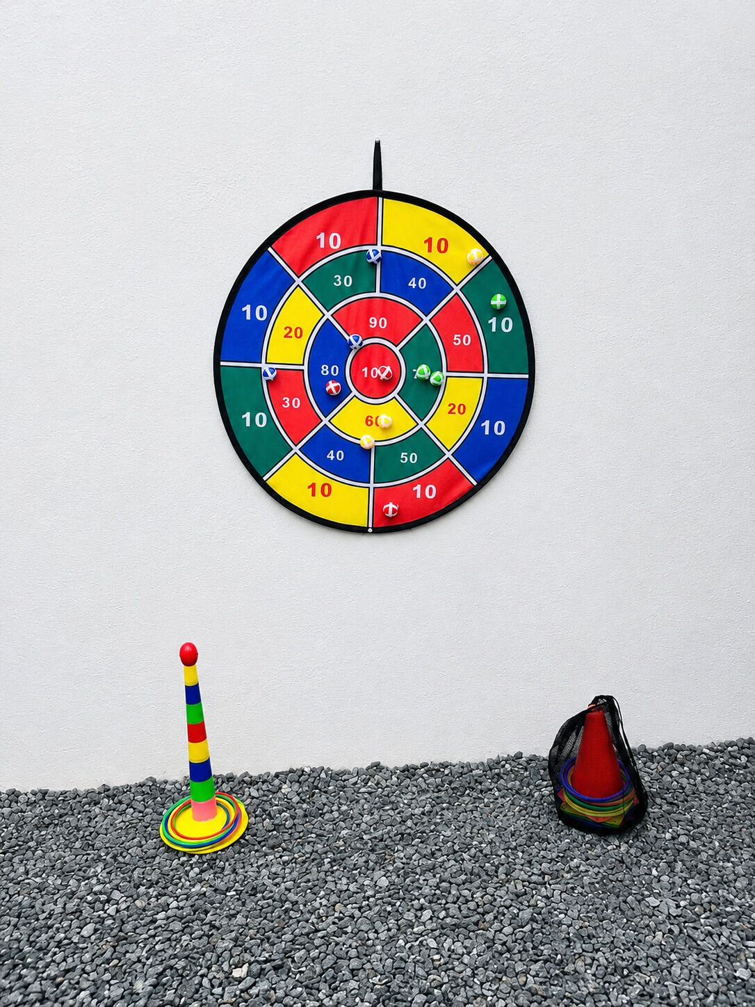 Une cible de fléchettes avec un centre, un cône coloré et un cône rouge, le tout posé sur une surface de gravier.