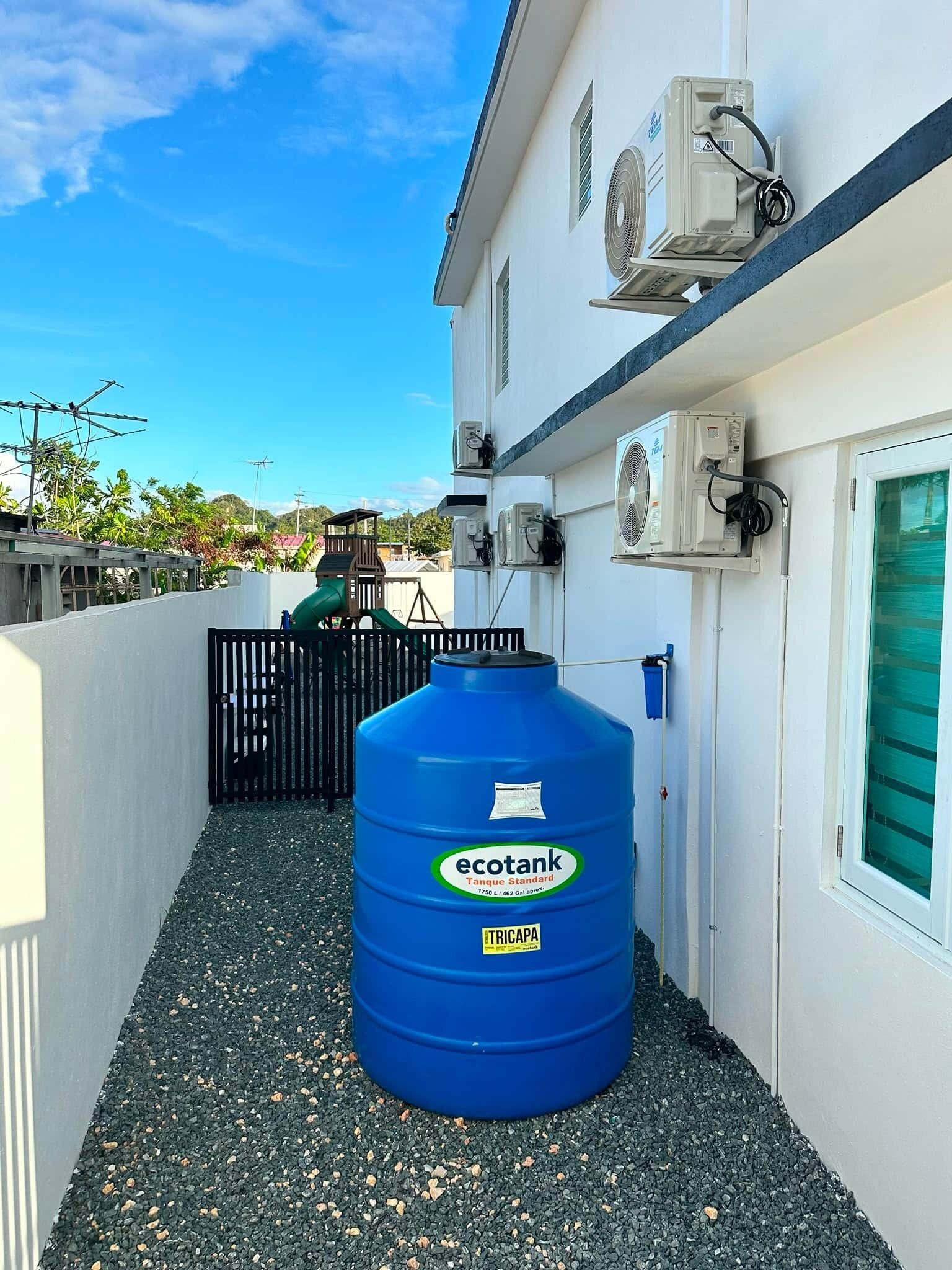 A blue storage tank labeled 'ecotank' and air conditioning units on a building's exterior.