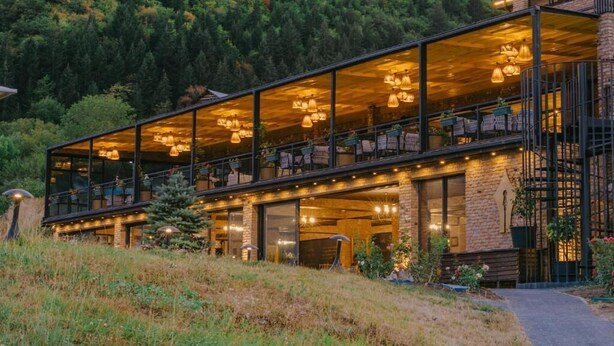 Un edificio moderno con amplios ventanales, asientos al aire libre y una escalera.