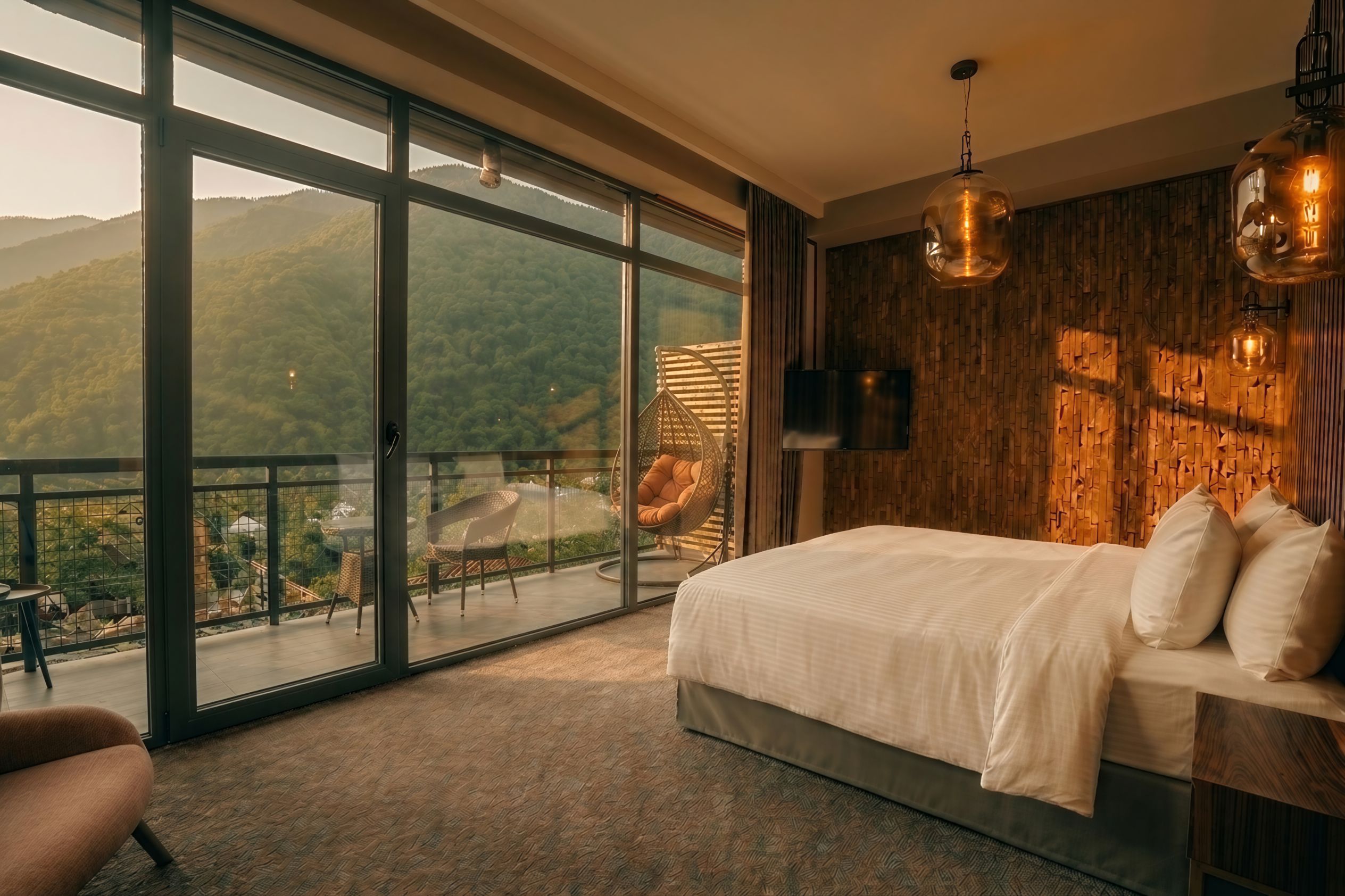 Une chambre dotée d’une grande porte-fenêtre coulissante donnant sur un balcon avec vue sur les montagnes.
