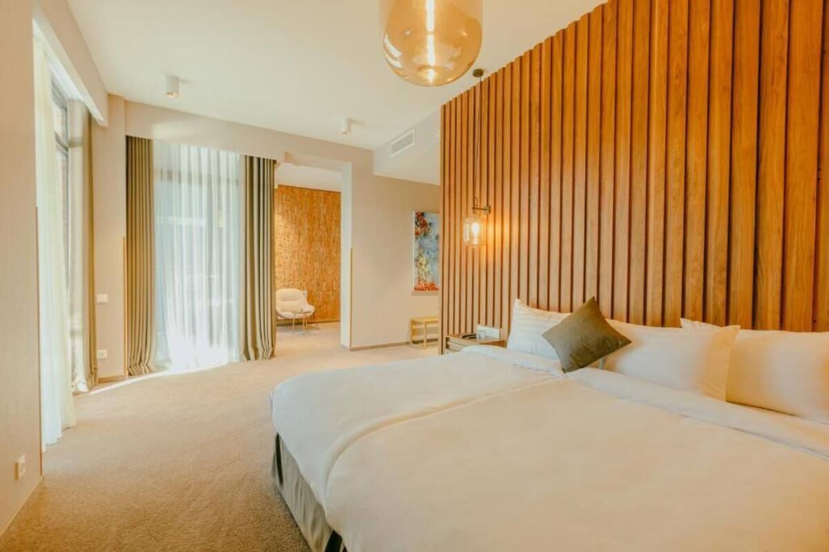 A hotel room with a large bed, a wooden accent wall, a painting, and a chair.